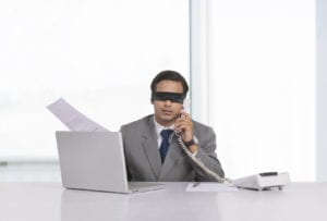 Blindfolded businessman working at desk in office